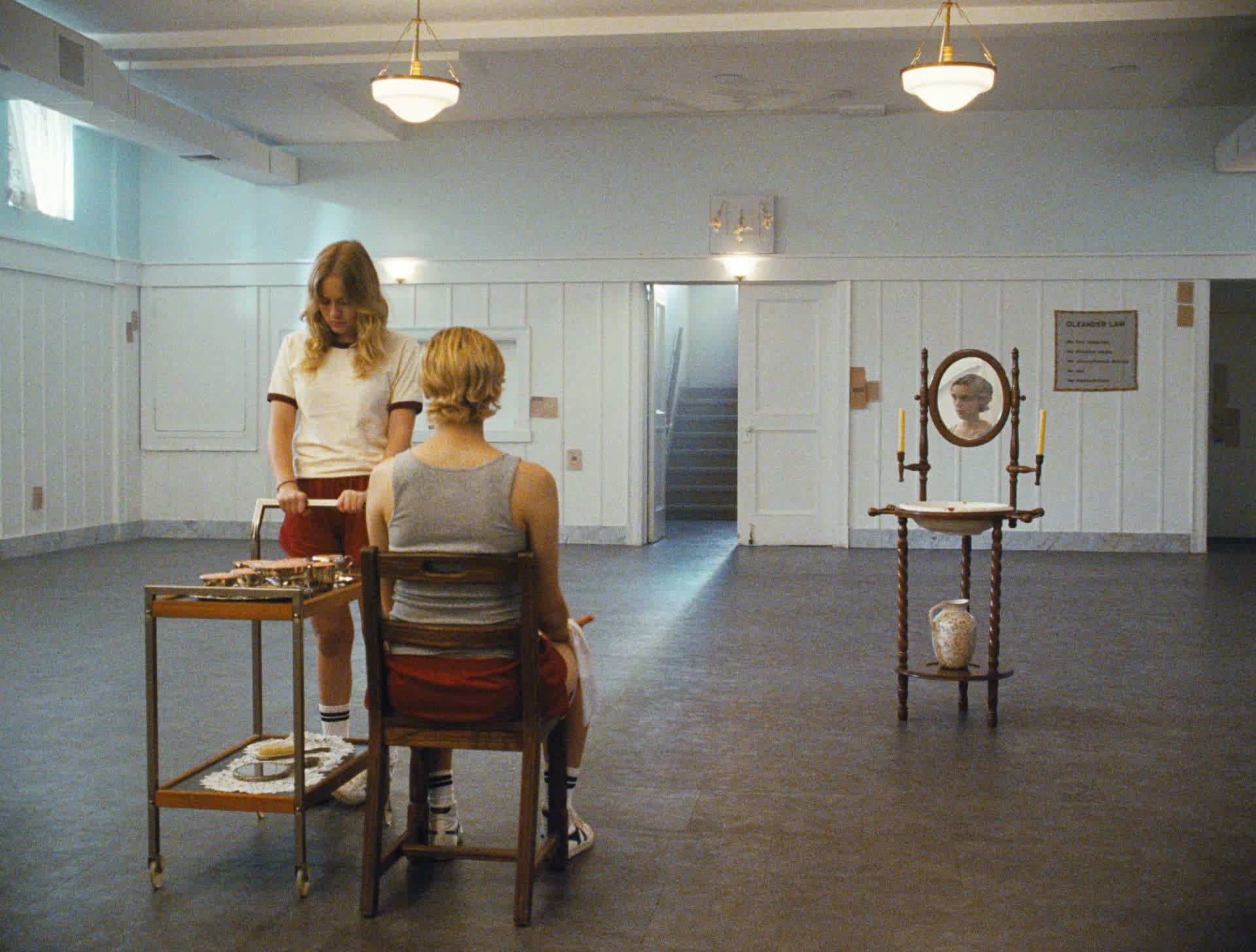 Two figures seated across a serving cart in a wide, symmetrical hall
